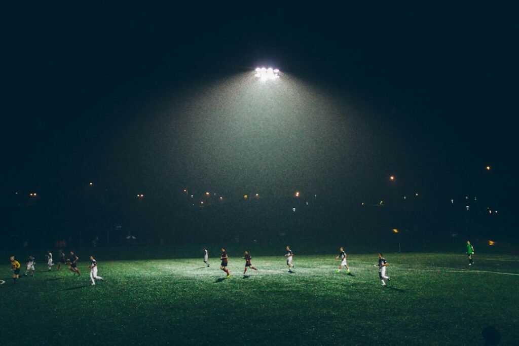 Partido de fútbol bajo iluminación artificial; fotografía de archivo de Abigail Keenan.