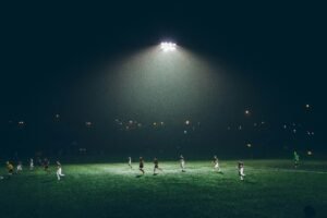 Partido de fútbol bajo iluminación artificial; fotografía de archivo de Abigail Keenan.
