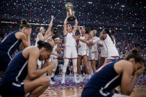 Jugadoras de baloncesto celebran el campeonato levantando el trofeo, mientras las rivales se lamentan entre confeti