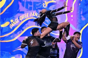Equipo de porrismo ejecuta una elevación en una imagen promocional del Invitacional de Campeones.