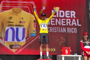 Cristian Rico en el podio de la Vuelta a Guatemala 2026 con el maillot amarillo de líder y una gorra del NU Colombia.